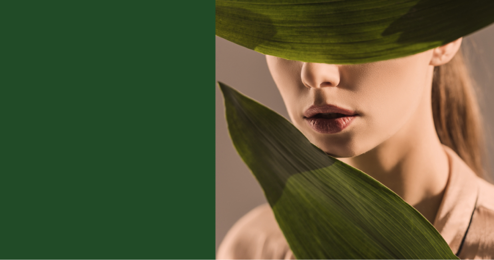 Woman with natural makeup partially covered by green leaves – Skin & Glow skincare theme